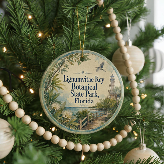 A round ornament hanging on a Christmas tree, featuring a scenic illustration of Lignum Vitae Key Botanical State Park, Florida.