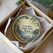 A round ornament with a scenic landscape of a lake, trees, and mountains, featuring the text "Lily Bay State Park, Maine" on it.