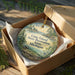 A decorative ornament in a wooden box, featuring a scenic landscape with a lighthouse and trees, with the text "Lime Island State Recreation Area, Michigan" printed on it.