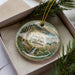 A decorative ornament in a box, featuring a scenic landscape with a waterfall and mountains, with the text "Limeklin State Park, California" prominently displayed.