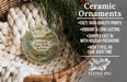 Ceramic ornaments, including a round ornament with a landscape scene, are displayed in a basket with greenery.
