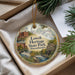 A decorative ornament with a scenic image of Lowell Heritage State Park in Massachusetts, featuring a river, buildings, and greenery.