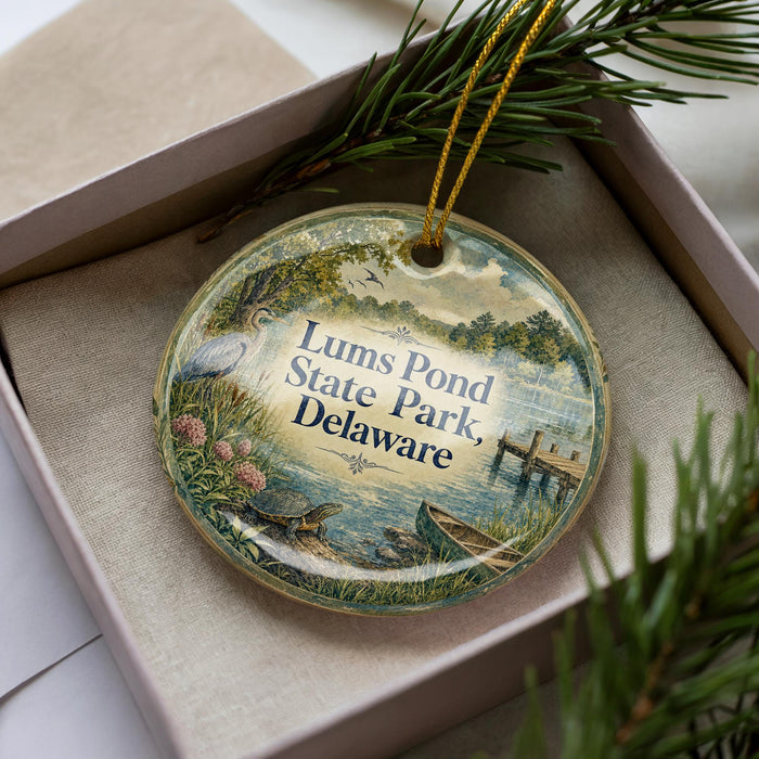 A decorative ornament in a box, featuring a scenic image of Lums Pond State Park, Delaware.