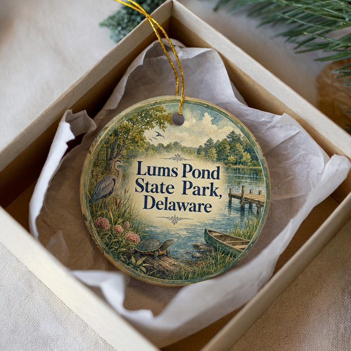 A round ornament with a scenic image of a pond and surrounding nature, including a bird, is displayed in a box.