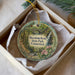 A decorative ornament in a box, featuring a scenic image of a park with a waterfall and greenery.