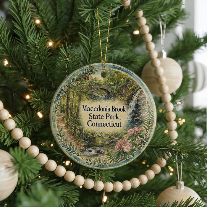 A round ornament hanging on a Christmas tree, featuring a scenic image of the state park in Connecticut.