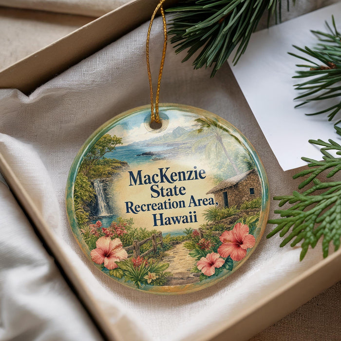 A decorative ornament with a tropical landscape, featuring a waterfall, palm trees, and flowers, is displayed in a box with pine branches.