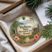A decorative ornament with a tropical landscape, featuring a waterfall, palm trees, and flowers, is displayed in a box with pine branches.