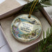A decorative ornament in a box, featuring a scenic image of Mackinac Island, Michigan.