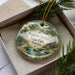 A decorative ornament featuring a scenic landscape of Magnolia Springs State Park, Georgia, with a watermill and greenery.