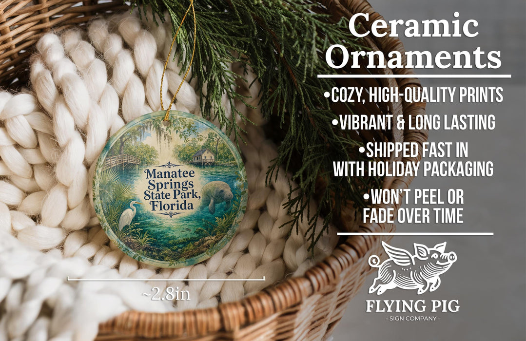 Ceramic ornaments, featuring a painting of Manatee Springs State Park, Florida, hanging in a basket with pine branches.