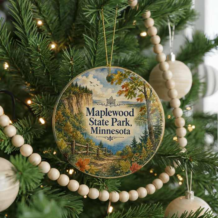 A round ornament hanging on a Christmas tree, featuring a scenic landscape with a path leading to a cliff and trees.