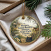 A round ornament with a vintage-style illustration of a house, typewriter, and horse, surrounded by greenery, placed in a box.