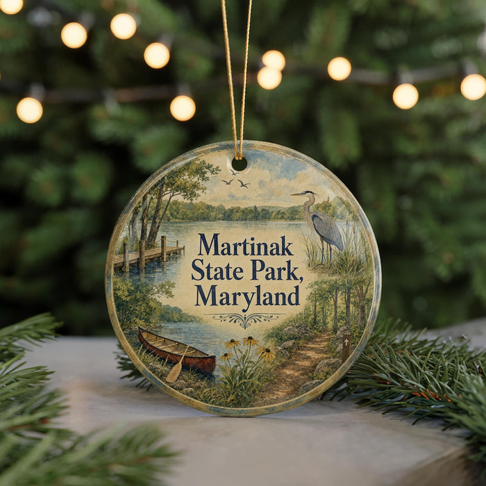 A round ornament with a painting of a lake, boat, and birds, surrounded by greenery and a string of lights.