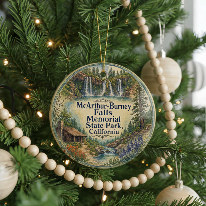 A circular ornament hanging on a Christmas tree, featuring a scenic landscape with a waterfall and a cabin.