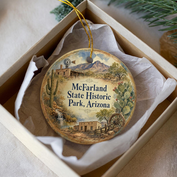 A decorative ornament in a box, featuring a desert landscape with a windmill, cactus, and other elements, along with the text "McFarland State Historic Park, Arizona".