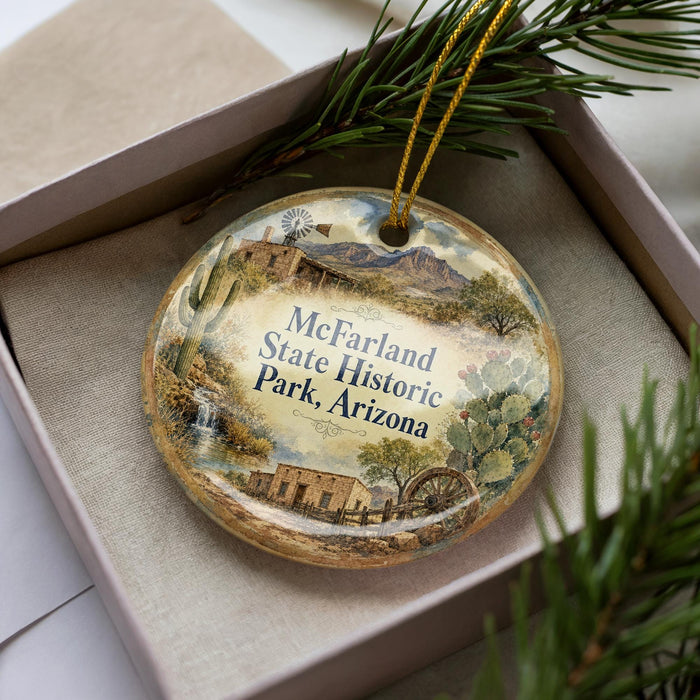A decorative ornament in a box, featuring a scenic landscape with a building, palm tree, and mountains, along with the text "McFarland State Historic Park, Arizona".