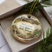 A decorative ornament in a box, featuring a scenic landscape with a building, palm tree, and mountains, along with the text "McFarland State Historic Park, Arizona".