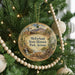 A round ornament hanging on a Christmas tree, featuring a desert landscape with a windmill and mountains in the background.