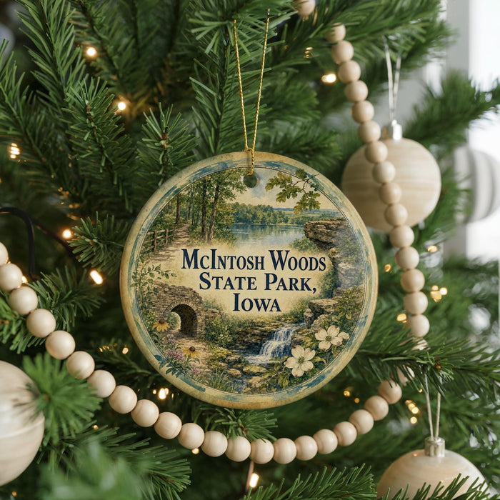 A round ornament on a Christmas tree, featuring a scenic image of McIntosh Woods State Park, Iowa.
