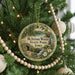 A round ornament on a Christmas tree, featuring a scenic image of McIntosh Woods State Park, Iowa.