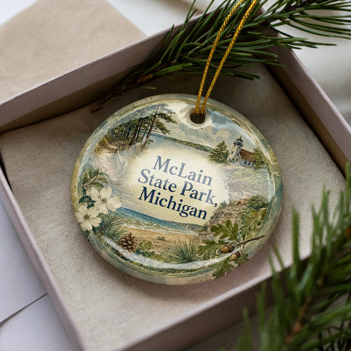 A decorative ornament in a box, featuring a scenic landscape with a lighthouse and pine trees.