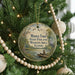 A round ornament hanging on a Christmas tree, featuring a scenic image of a lake surrounded by trees and wildlife.