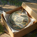 A round ornament in a box, featuring a scenic landscape with a lake, trees, and a cabin, along with the text "Mille Lacs Kathio State Park, Minnesota".