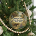 A round ornament hanging on a Christmas tree, featuring a scenic landscape with a bird, a castle, and a waterfall.