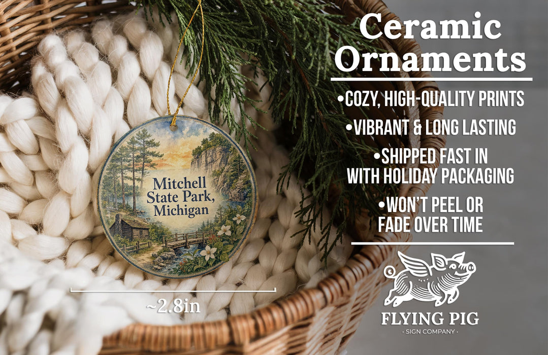 Ceramic ornaments, featuring a painting of Mitchell State Park, Michigan, hanging in a basket with pine branches.