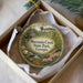 A decorative ornament in a box, featuring a scenic landscape with a house, trees, and flowers, along with the text "Moccasin Creek State Park, Georgia".