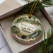 A decorative ornament in a box, featuring a scenic landscape with a waterfall and trees, with the text "Monte Sano State Park, Alabama" prominently displayed.