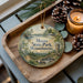 A wooden tray with a decorative ornament featuring a scenic landscape of Moore State Park, Massachusetts, and pine cones.