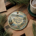A decorative ornament featuring a moose and pine trees, with the text "Moose Point State Park, Maine" displayed on it, is placed on a wooden surface alongside a cup of coffee and some pine branches.