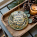 A decorative ornament featuring a scenic image of Mount San Jacinto State Park, California, with pine cones and a lit candle on a wooden tray.