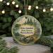 A round ornament with a scenic forest landscape and a deer, hanging on a string.