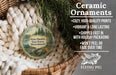 Ceramic ornaments, including a round ornament with a forest scene and a wicker basket, are displayed on a bed with a white blanket.
