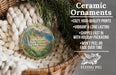 Ceramic ornaments, featuring a round ornament with a tropical landscape design, are displayed in a woven basket.