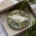 A decorative ornament in a box, featuring a scenic image of the Natural Bridge State Resort Park in Kentucky.