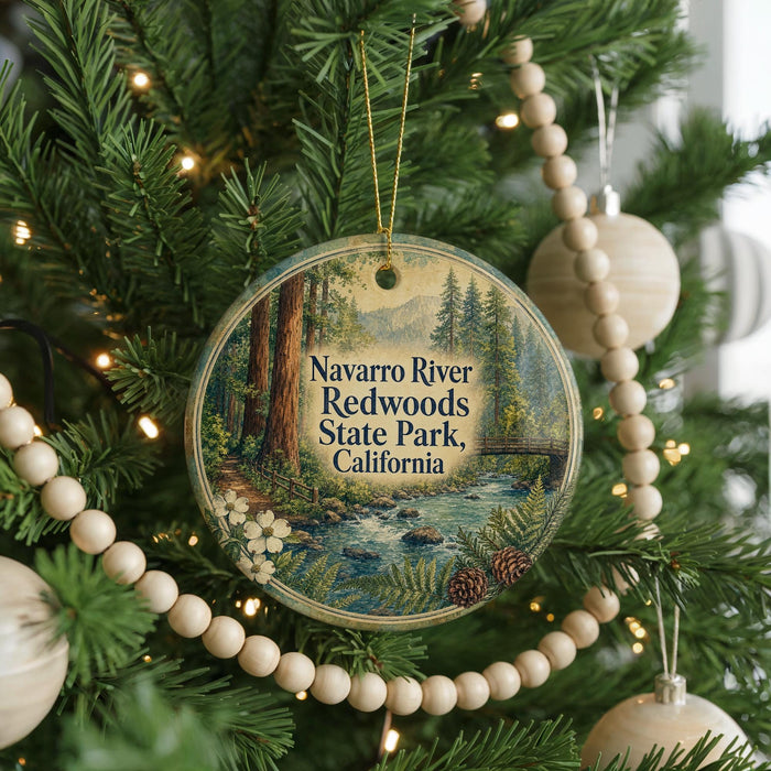 A round ornament hanging on a Christmas tree, featuring a scenic image of the Navarro River and Redwoods State Park in California.