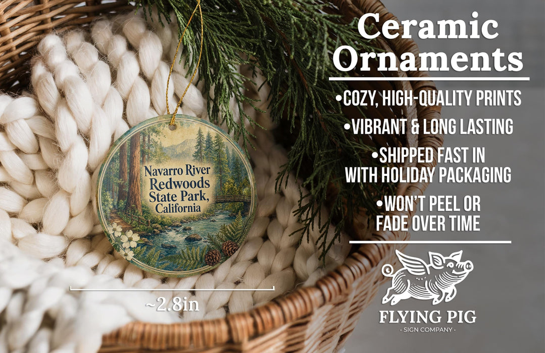 Ceramic ornaments, featuring a round ornament with a forest scene and text, hanging in a basket with pine branches.