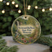 A round ornament with a scenic image of a waterfall, flowers, and a bird, hanging from a string.