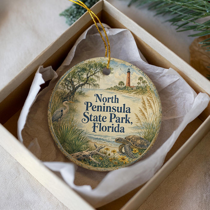 A decorative ornament in a box, featuring a scenic image of North Peninsula State Park, Florida.