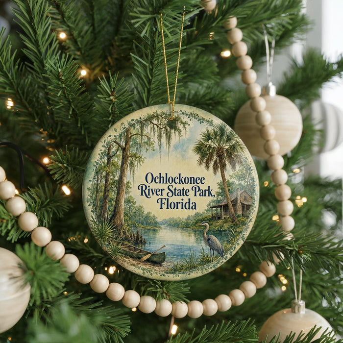 A round ornament hanging on a Christmas tree, featuring a scenic view of Ochlockonee River State Park, Florida.