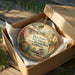 A decorative ornament in a box, featuring an illustration of a historic building and landscape, with the text "Old Town San Diego State Historic Park, California" printed on it.