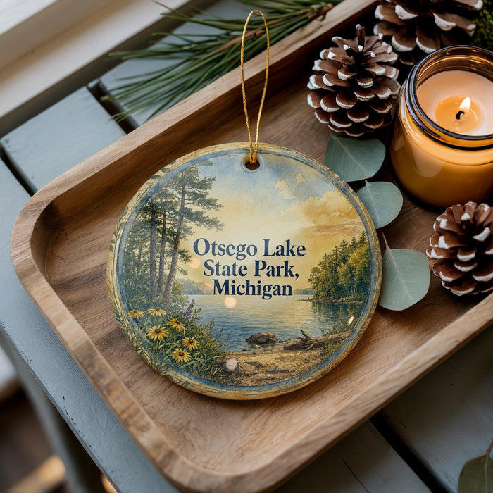 A wooden tray with a decorative ornament featuring a scenic lake and pine trees, along with pine cones and a lit candle.