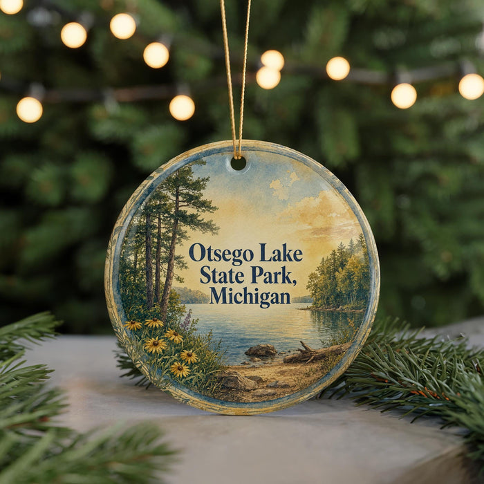 A circular ornament with a painting of a lake and trees, featuring the text "Osego Lake State Park, Michigan" on it.