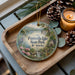A decorative ornament featuring a scenic image of Paintsville Lake, Paintsville State Park, and Kentucky, with pine cones and a lit candle on a wooden tray.