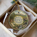 A decorative ornament in a box, featuring a scenic landscape with a mountain, a bridge, and a stream.