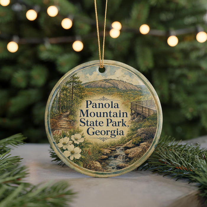 A circular ornament with a scenic image of Panola Mountain State Park, Georgia, surrounded by pine branches and twinkling lights.